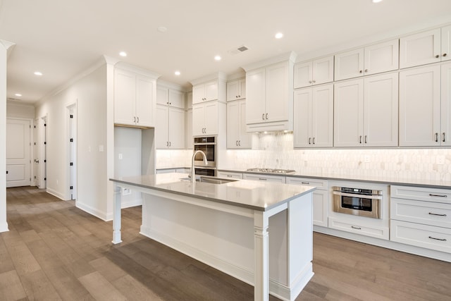 kitchen featuring white cabinetry, sink, stainless steel gas cooktop, an island with sink, and hardwood / wood-style flooring