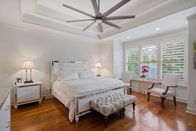 bedroom with a raised ceiling, ceiling fan, crown molding, and dark wood-type flooring