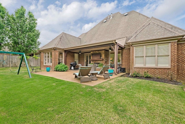 rear view of house with a playground, a fireplace, a yard, and a patio