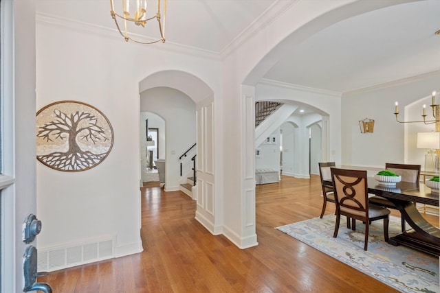 entryway with hardwood / wood-style flooring, crown molding, and a chandelier