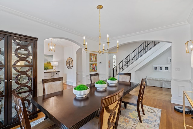 dining space with ornamental molding, a notable chandelier, and hardwood / wood-style flooring