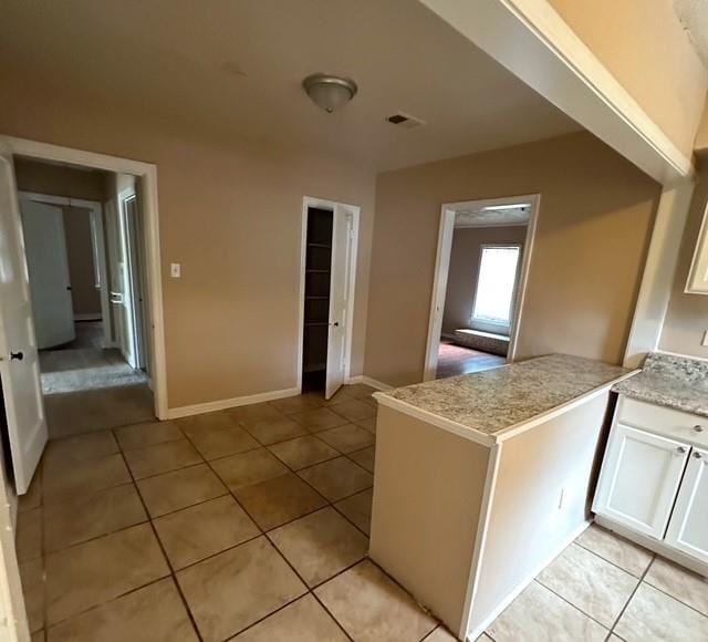 kitchen with light tile patterned flooring, white cabinetry, and kitchen peninsula