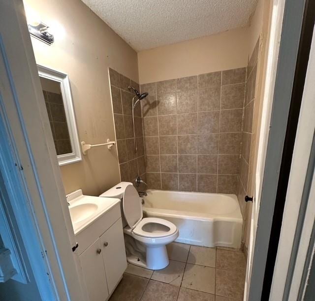 full bathroom with vanity, tile patterned floors, tiled shower / bath, toilet, and a textured ceiling