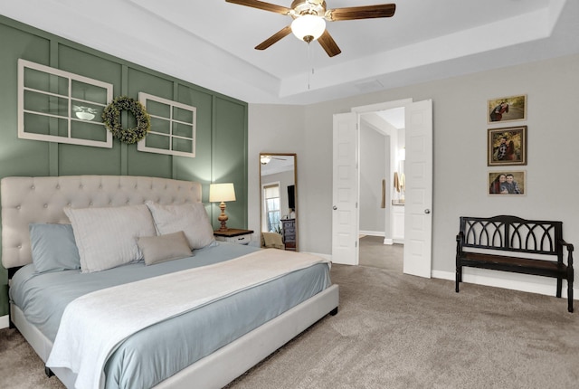 bedroom with carpet floors, a tray ceiling, and ceiling fan