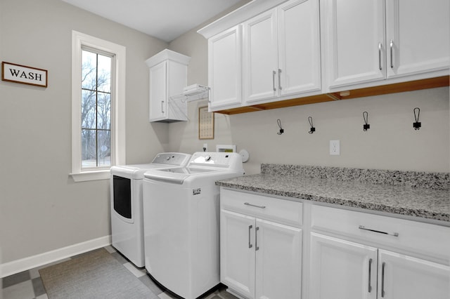 clothes washing area featuring cabinets and washer and clothes dryer