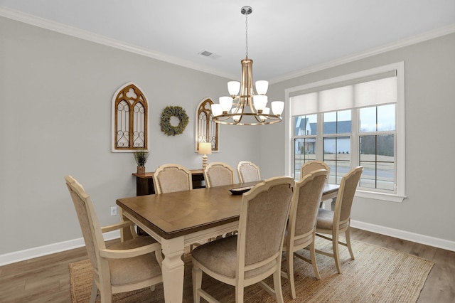 dining area with ornamental molding, dark wood-type flooring, and an inviting chandelier