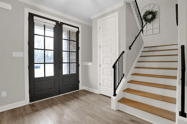 foyer with french doors, light wood-type flooring, and ornamental molding