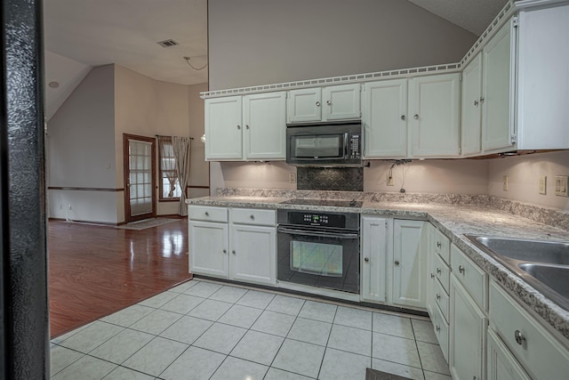 kitchen featuring black appliances, lofted ceiling, white cabinets, and light tile patterned floors