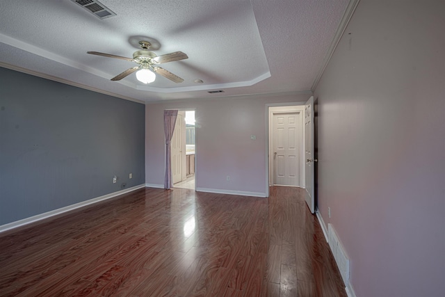 unfurnished room featuring a raised ceiling, ceiling fan, wood-type flooring, and a textured ceiling