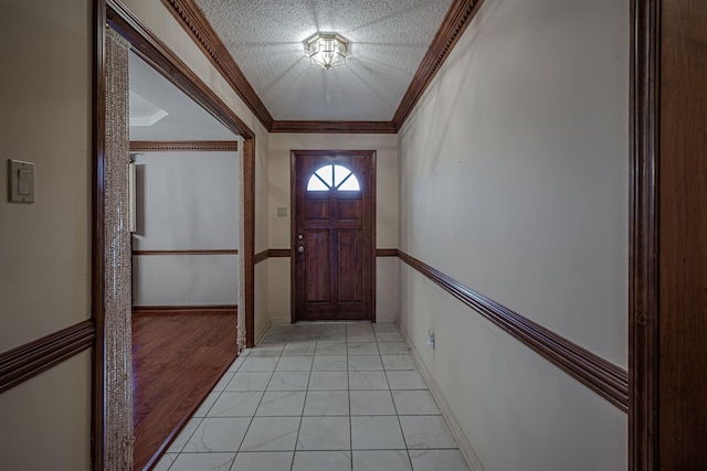 entryway with light tile patterned floors, a textured ceiling, and ornamental molding