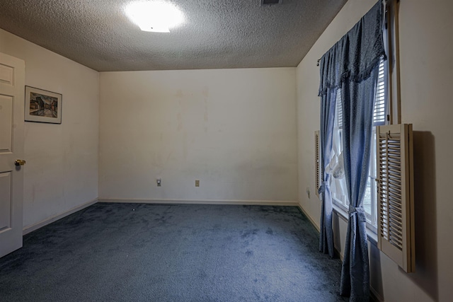 empty room with dark carpet and a textured ceiling