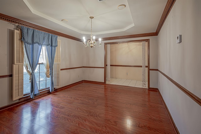 unfurnished dining area with a chandelier, wood-type flooring, a raised ceiling, and crown molding