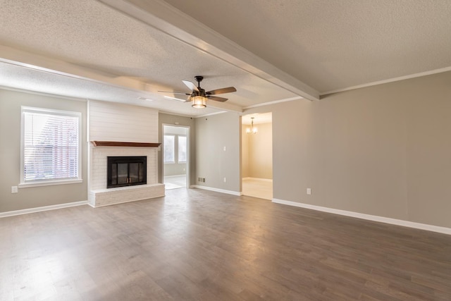 unfurnished living room featuring beamed ceiling, dark hardwood / wood-style floors, a textured ceiling, and a brick fireplace