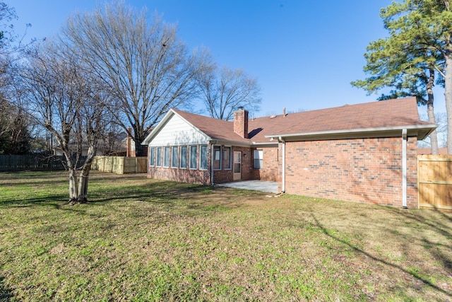 back of property featuring a patio, a sunroom, and a lawn