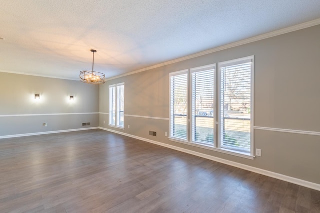 empty room with a chandelier, ornamental molding, a textured ceiling, and dark wood-type flooring