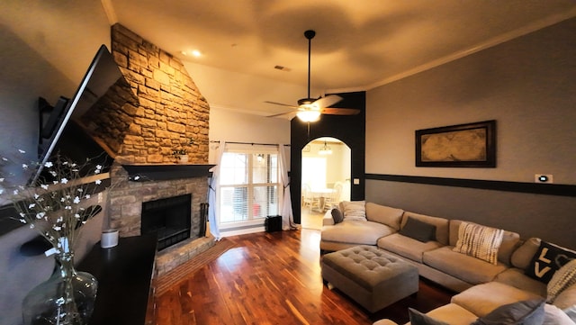 living room with ceiling fan, ornamental molding, a stone fireplace, and dark hardwood / wood-style flooring