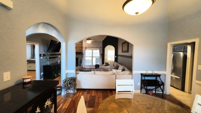 living room featuring ceiling fan, wood-type flooring, and a stone fireplace