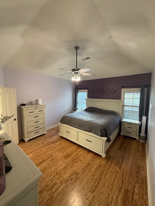 bedroom featuring lofted ceiling, a textured ceiling, and light hardwood / wood-style floors