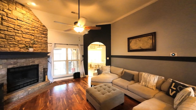 living room with a stone fireplace, dark hardwood / wood-style floors, lofted ceiling, ceiling fan, and crown molding