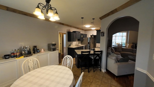 tiled dining room with sink and an inviting chandelier