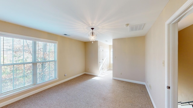 carpeted spare room with baseboard heating and an inviting chandelier