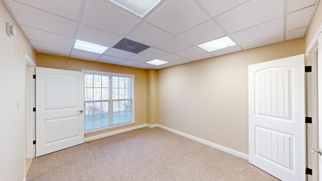 empty room with a paneled ceiling and light carpet