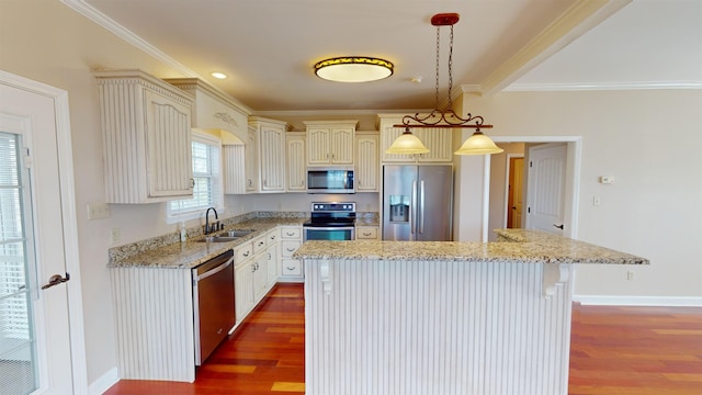 kitchen with sink, stainless steel appliances, decorative light fixtures, a kitchen island, and ornamental molding