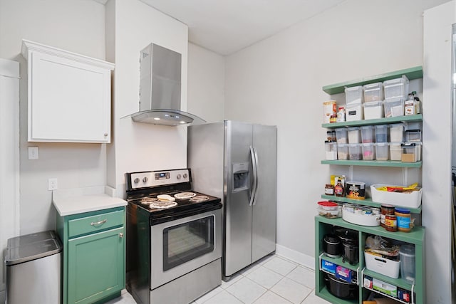 kitchen with white cabinetry, wall chimney range hood, green cabinets, light tile patterned flooring, and appliances with stainless steel finishes