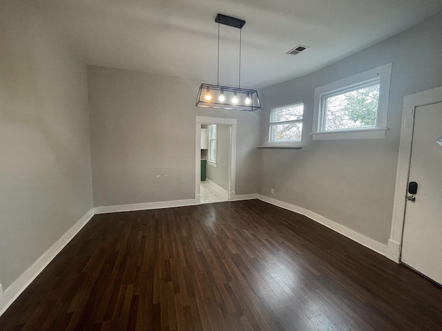 unfurnished dining area with baseboards, visible vents, and wood finished floors