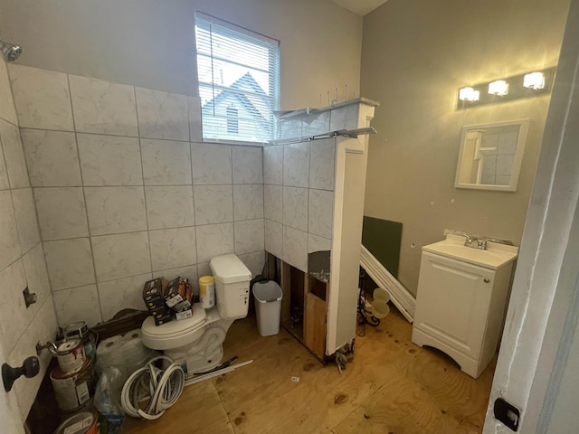 bathroom with toilet, tile walls, and vanity