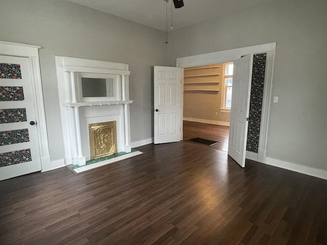 unfurnished living room featuring a fireplace with flush hearth, dark wood-type flooring, ceiling fan, and baseboards