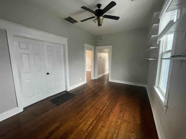 unfurnished bedroom featuring dark wood-type flooring, a closet, visible vents, and baseboards