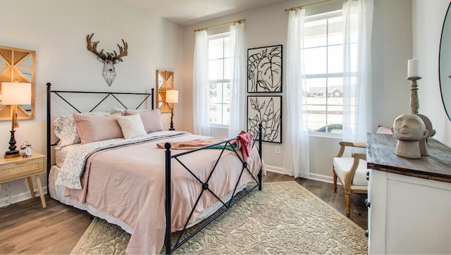 bedroom with multiple windows, baseboards, and wood finished floors