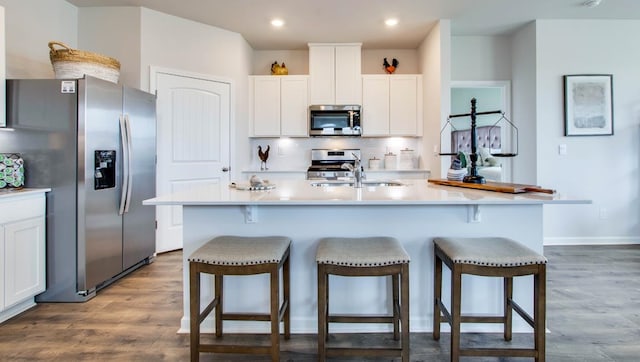 kitchen featuring white cabinetry, stainless steel appliances, and an island with sink