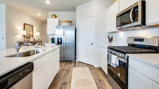 kitchen featuring a sink, stainless steel appliances, light wood-style floors, white cabinetry, and backsplash