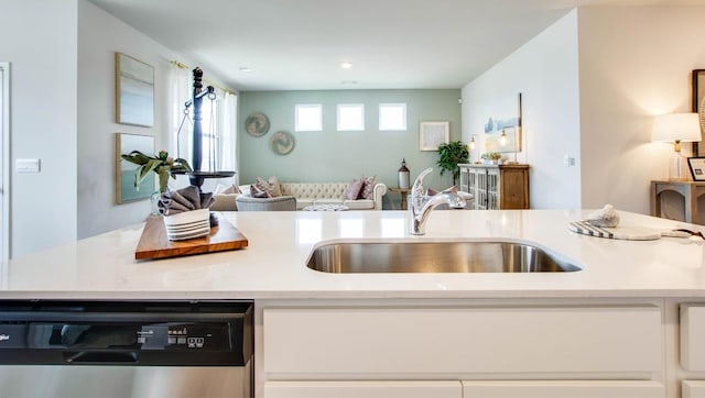 kitchen with light countertops, open floor plan, white cabinetry, a sink, and dishwasher