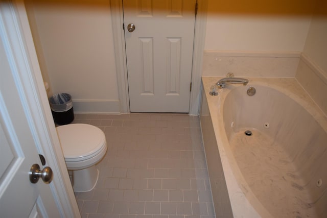 bathroom featuring tile patterned flooring, a washtub, and toilet