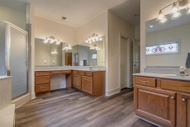 bathroom with hardwood / wood-style flooring, vanity, a textured ceiling, and walk in shower