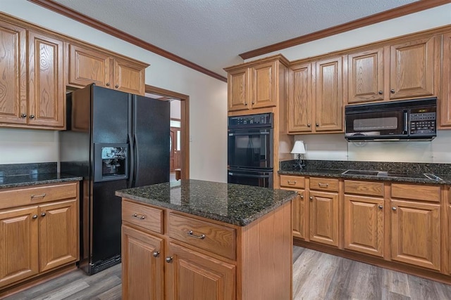 kitchen with crown molding, hardwood / wood-style floors, a kitchen island, and black appliances