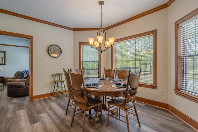 dining area featuring a textured ceiling, ornamental molding, a notable chandelier, and hardwood / wood-style flooring