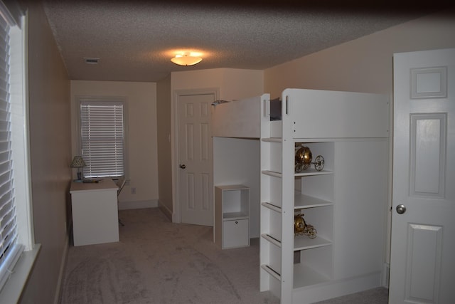 unfurnished bedroom featuring a textured ceiling and light carpet