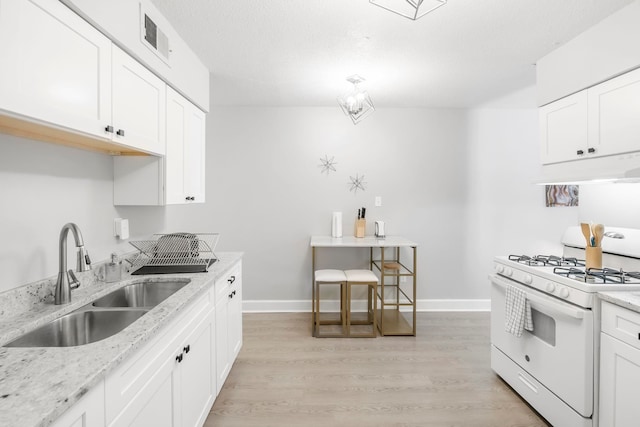 kitchen featuring light stone counters, white cabinetry, white gas range, and sink