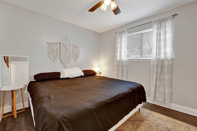 bedroom with a textured ceiling, ceiling fan, and dark wood-type flooring