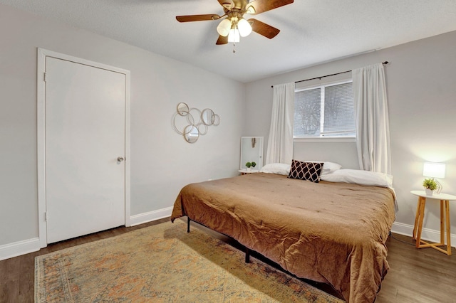 bedroom with ceiling fan, wood-type flooring, and a textured ceiling