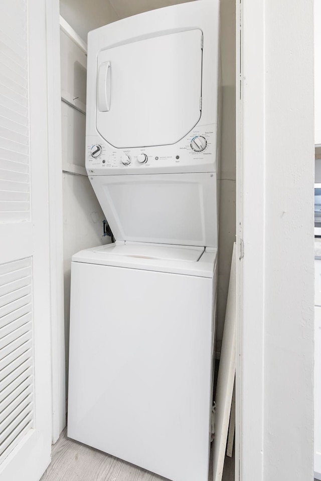 clothes washing area with stacked washer and dryer and light hardwood / wood-style floors