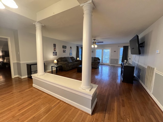 unfurnished living room featuring decorative columns, ceiling fan, and wood-type flooring