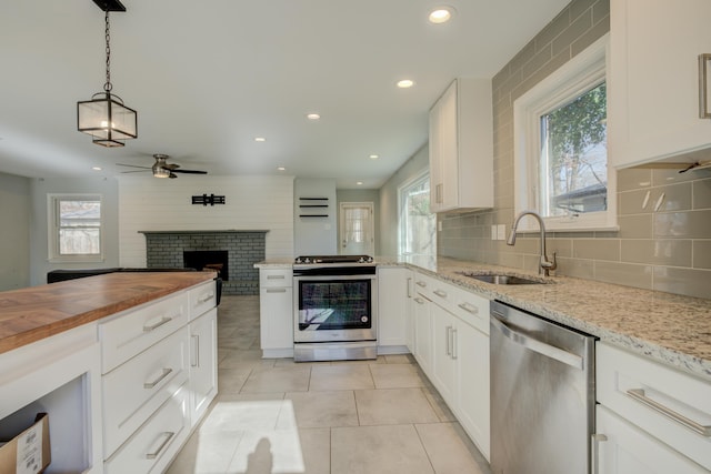 kitchen featuring ceiling fan, sink, stainless steel appliances, decorative light fixtures, and white cabinets