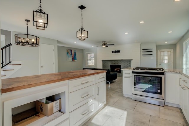 kitchen with white cabinets, decorative light fixtures, gas stove, and wooden counters