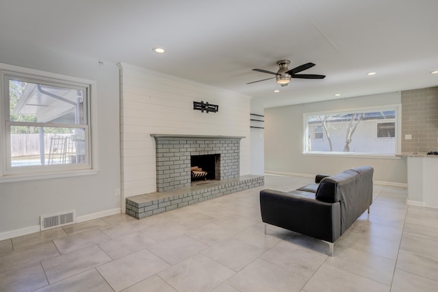 tiled living room featuring ceiling fan and a fireplace