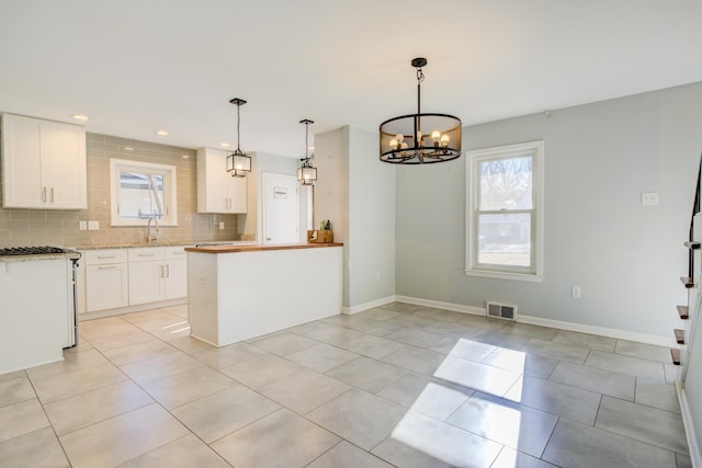 kitchen with backsplash, sink, a notable chandelier, white cabinetry, and hanging light fixtures